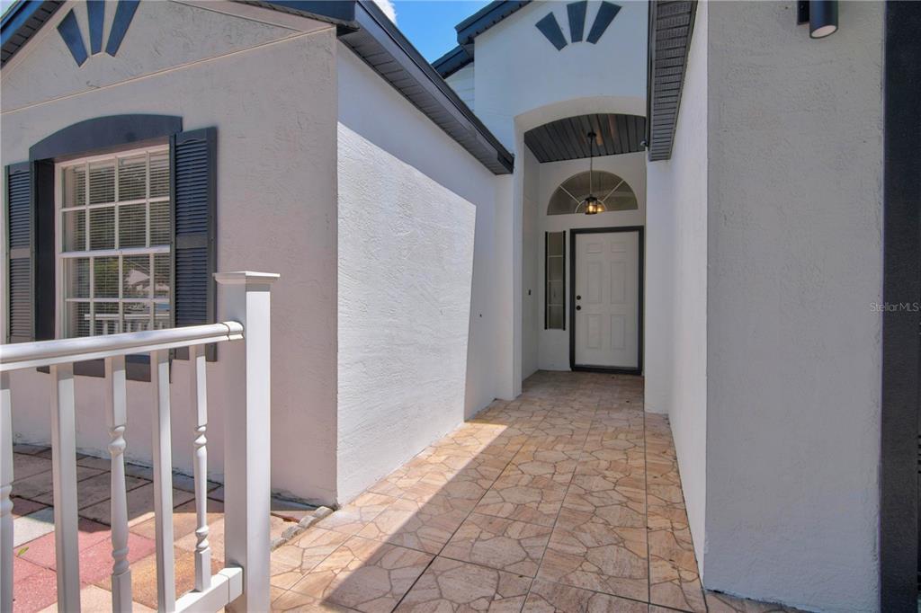 A covered entryway features a tiled walkway leading to a white front door — 314 RIDGE COURT, APOPKA, FL