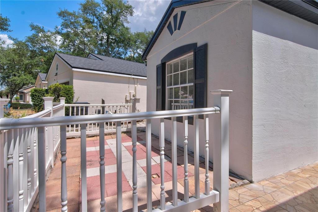 A white house exterior features a small fenced patio with red and tan pavers — 314 RIDGE COURT, APOPKA, FL