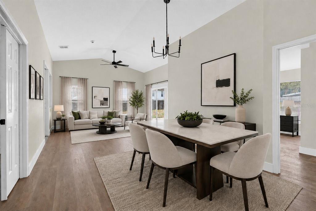An open-concept dining and living area features light wood flooring, neutral furniture, and vaulted ceilings — 314 RIDGE COURT, APOPKA, FL
