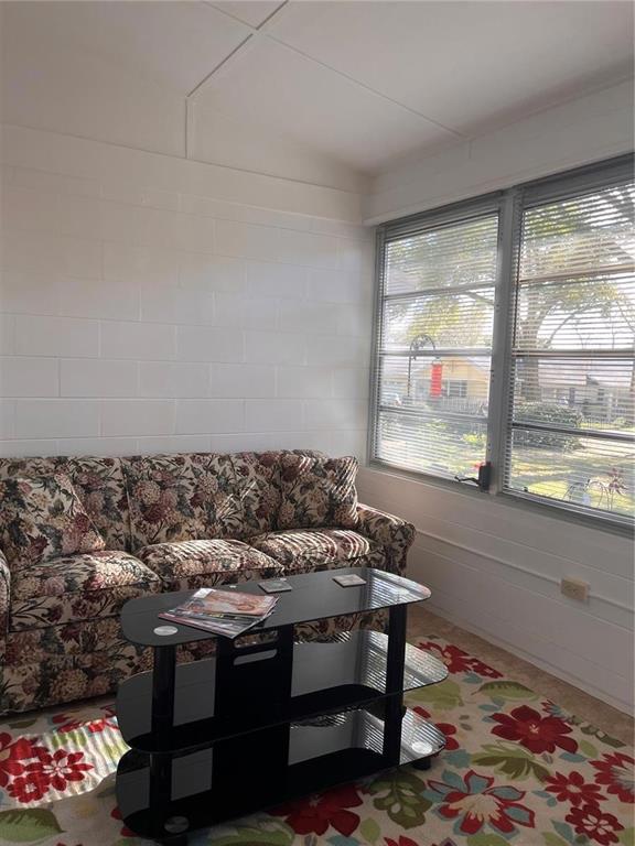 A sunroom features a floral sofa, a glass coffee table, and a white block wall — 8757 SW 97TH LANE ROAD UNIT C, OCALA, FL