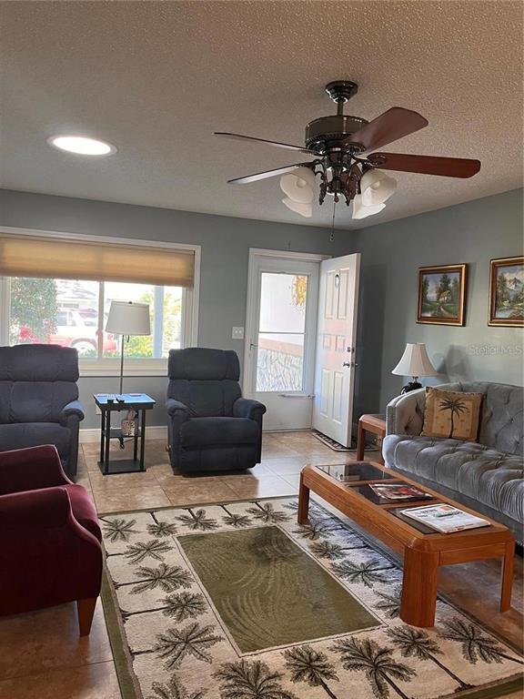 A living room features a ceiling fan, tiled floors, a rug, and various seating options — 8757 SW 97TH LANE ROAD UNIT C, OCALA, FL