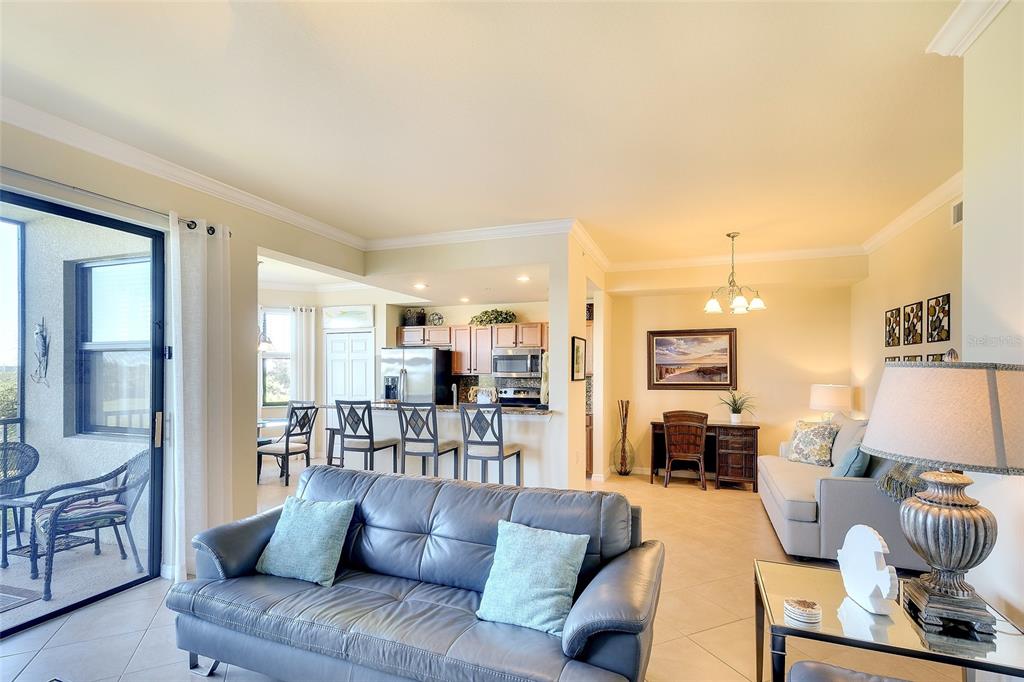A living room with a leather sofa, dining area, and kitchen with bar seating — 7121 RIVER HAMMOCK DRIVE UNIT 303, BRADENTON, FL