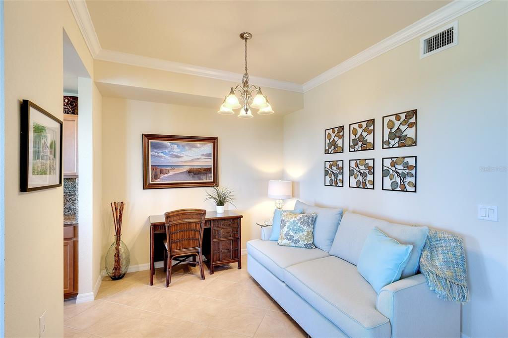 A living area features a light blue sofa, a wooden desk, and wall-mounted artwork — 7121 RIVER HAMMOCK DRIVE UNIT 303, BRADENTON, FL