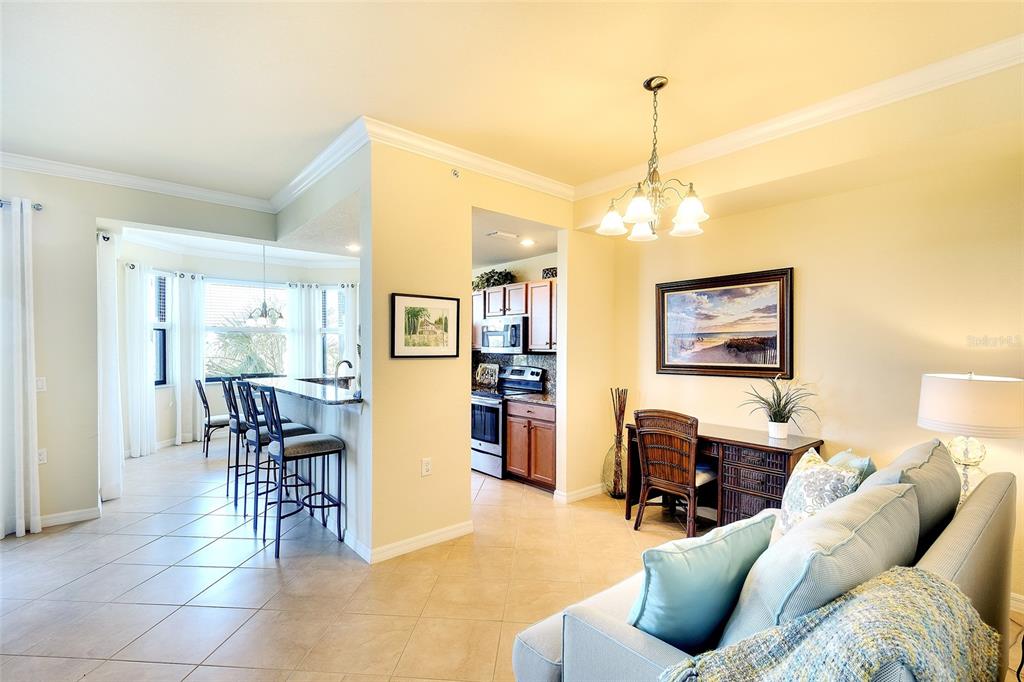 A living area with a desk, kitchen bar seating, and a view into the kitchen — 7121 RIVER HAMMOCK DRIVE UNIT 303, BRADENTON, FL