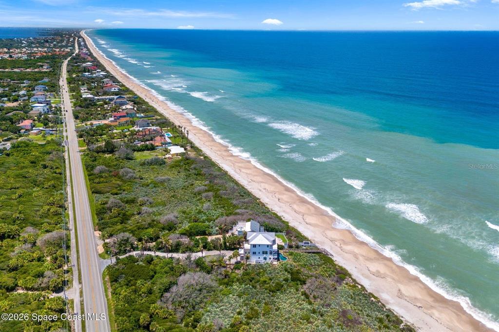 An aerial view shows a coastal house situated between a road and the ocean — 6105 S HIGHWAY A1A, MELBOURNE BEACH, FL