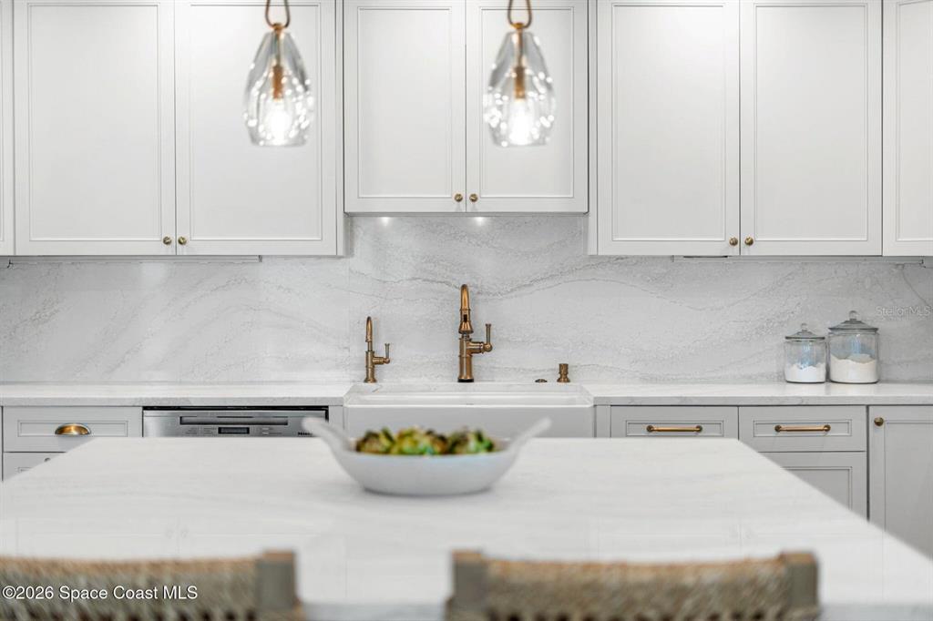A kitchen features white cabinetry, a marble backsplash, a farmhouse sink, and a central island — 6105 S HIGHWAY A1A, MELBOURNE BEACH, FL