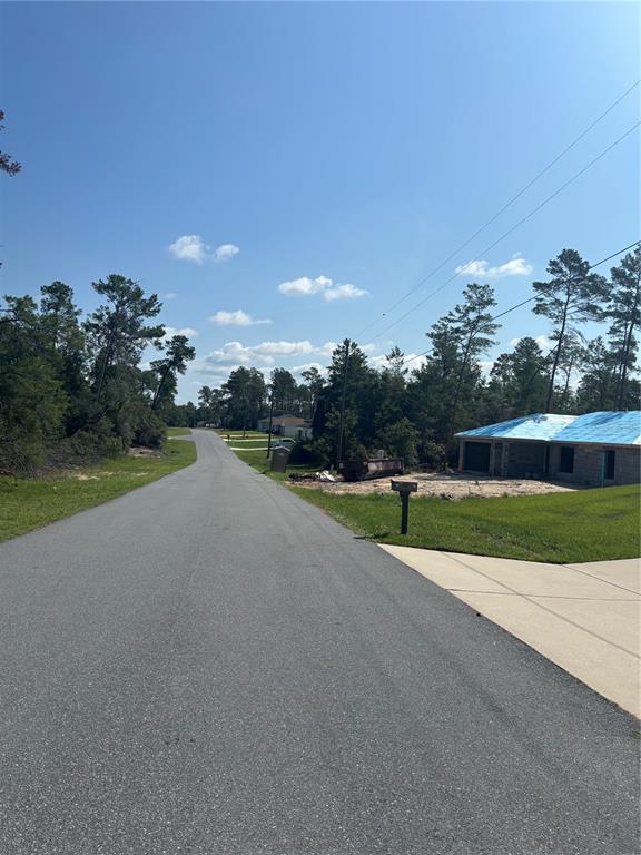 A paved road leads past a house under construction with a blue roof — 16698 SW 21ST CIRCLE, OCALA, FL