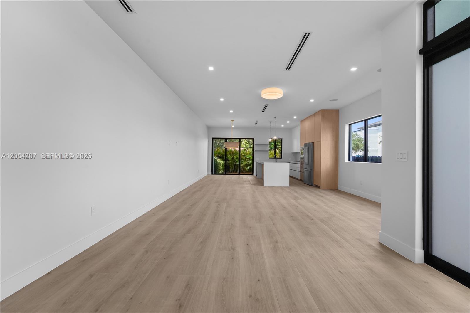 This open-concept living area features light wood flooring, white walls, and a modern kitchen — 2735 SW 23rd Ter, Miami FL 33145, MIAMI, FL