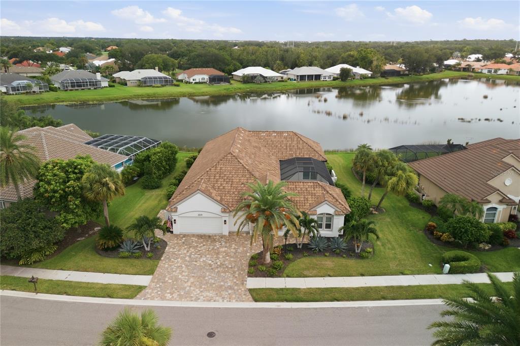 The exterior of a white house features a paved driveway, double front doors, and landscaping — 309 S STONE BRIAR CREEK DRIVE, VENICE, FL