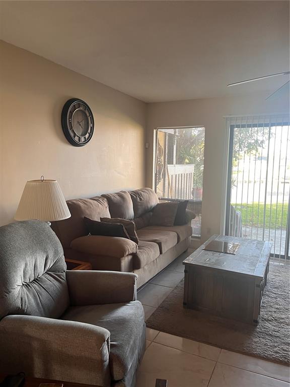 A living room features a brown sofa, a gray armchair, a coffee table, and a clock — 58 CLUB HOUSE DRIVE UNIT 104, PALM COAST, FL