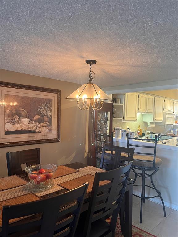 A dining area with a glass pendant light, dark wood furniture, and an adjacent kitchen — 58 CLUB HOUSE DRIVE UNIT 104, PALM COAST, FL