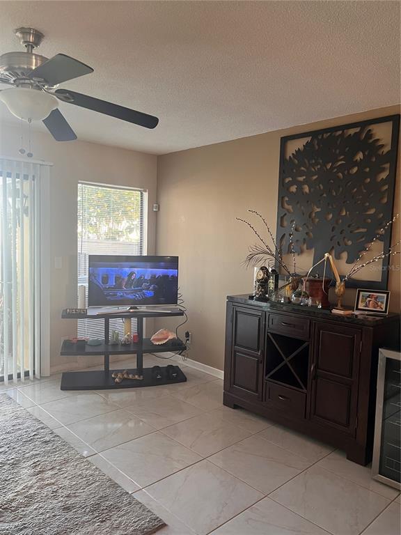 A living room features tile flooring, a ceiling fan, a television stand, and a dark wood sideboard — 58 CLUB HOUSE DRIVE UNIT 104, PALM COAST, FL