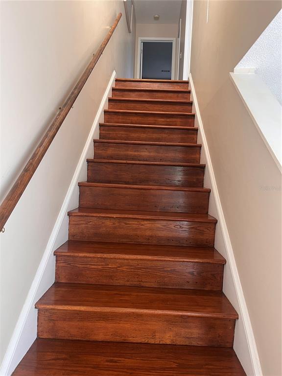 A straight wooden staircase with a handrail leads to a doorway at the top — 58 CLUB HOUSE DRIVE UNIT 104, PALM COAST, FL