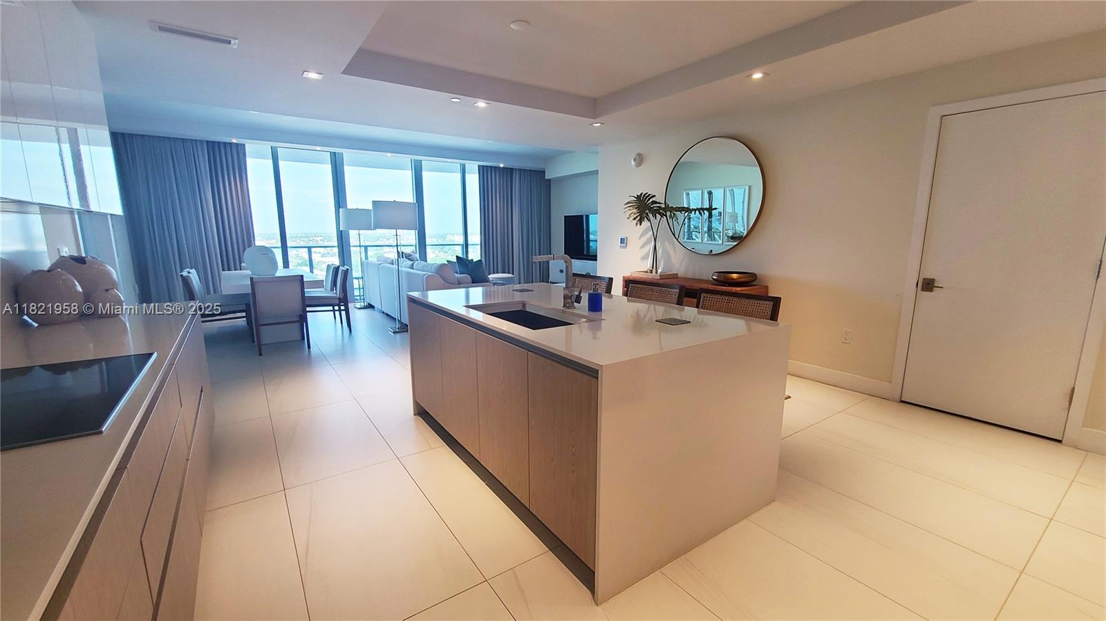 A modern kitchen features a central island with a sink and light wood cabinetry — 3100 N Ocean Drive # 1206, Singer Island FL 33404, SINGER ISLAND, FL