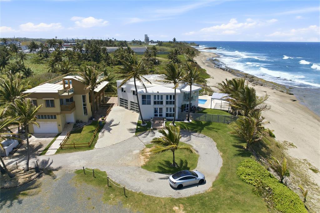 An aerial view shows two beachfront houses with palm trees, a circular driveway, and a car — MARFIL ST. TESORO DEL MAR IN LAS PALMAS, HATILLO, PR