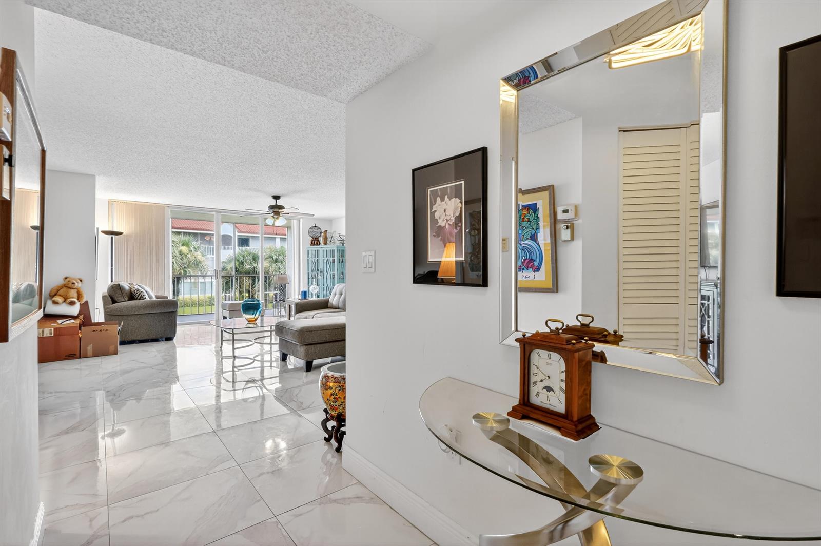 A bright, tiled entryway leads into a living room with a balcony and sliding doors — 110 Half Moon Circle # D2, Hypoluxo FL 33462, HYPOLUXO, FL