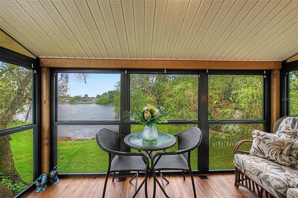 A screened-in porch with wood-look flooring, a small bistro set, and a view of water — 4015 DAVIT DRIVE, NEW PORT RICHEY, FL