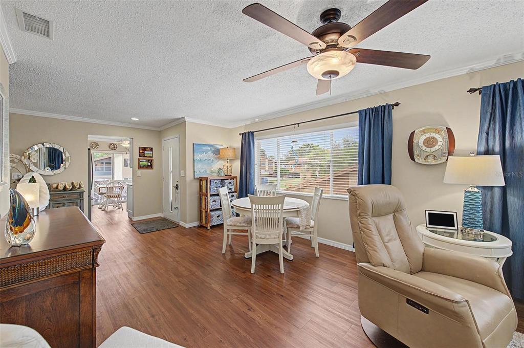A living and dining area features wood-look flooring, a ceiling fan, and a large window — 4015 DAVIT DRIVE, NEW PORT RICHEY, FL