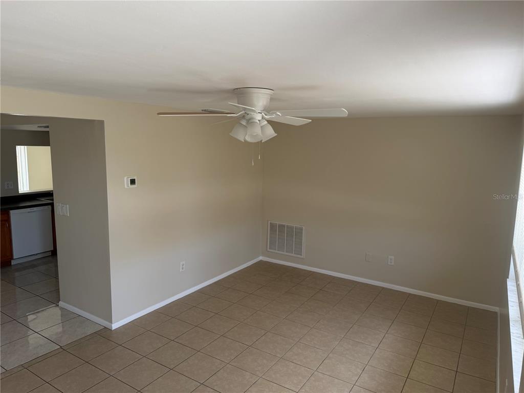An empty room with beige walls, tile flooring, and a ceiling fan — 3452 COLUMBUS DRIVE, HOLIDAY, FL