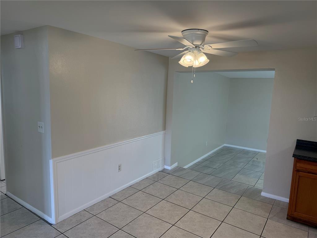 A dining area with tile flooring, a ceiling fan, and white wainscoting on the wall — 3452 COLUMBUS DRIVE, HOLIDAY, FL