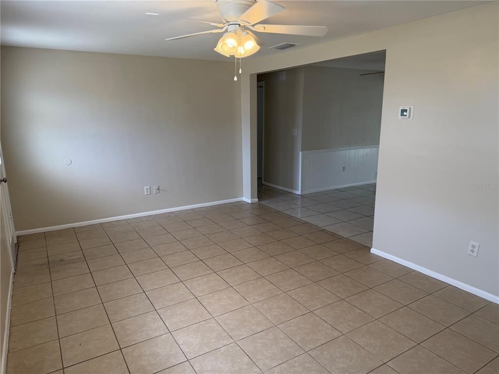 An empty room with tan tile flooring, beige walls, and a ceiling fan — 3452 COLUMBUS DRIVE, HOLIDAY, FL