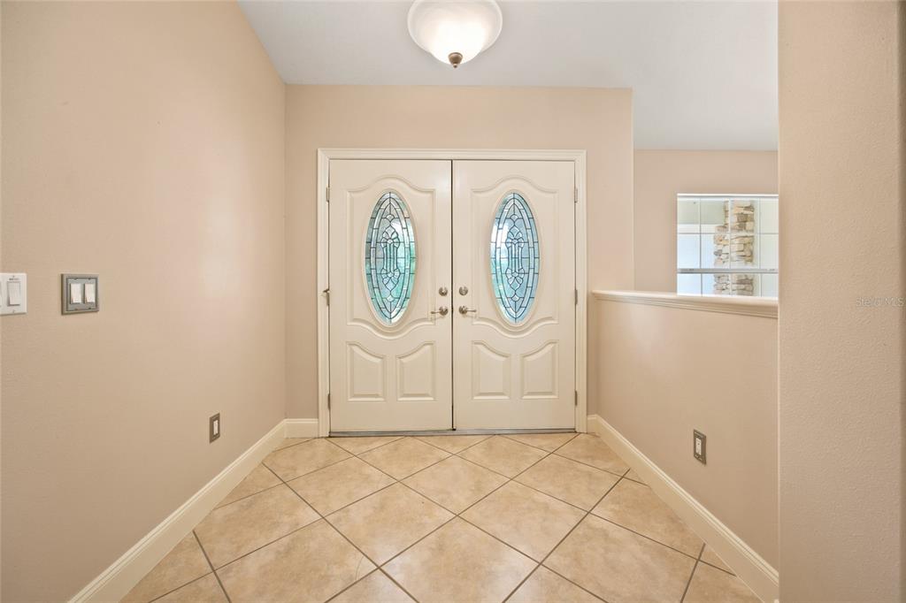 An entryway features beige walls, tiled floors, and a double front door with glass inserts — 5259 SE 38TH STREET, OCALA, FL