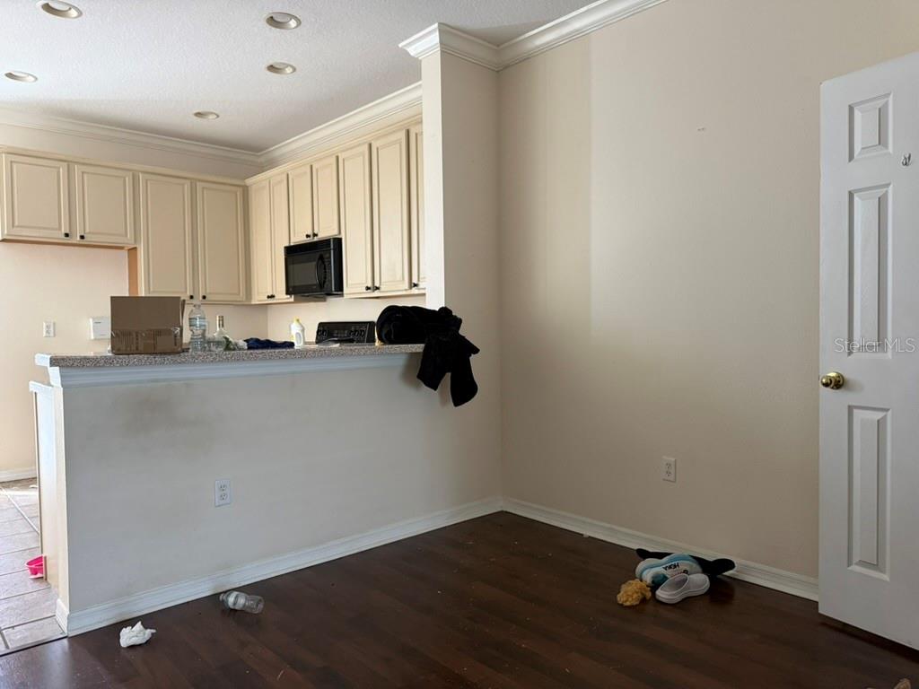 A kitchen with cream cabinets and a breakfast bar overlooks a room with wood flooring — 11537 DECLARATION DRIVE, TAMPA, FL