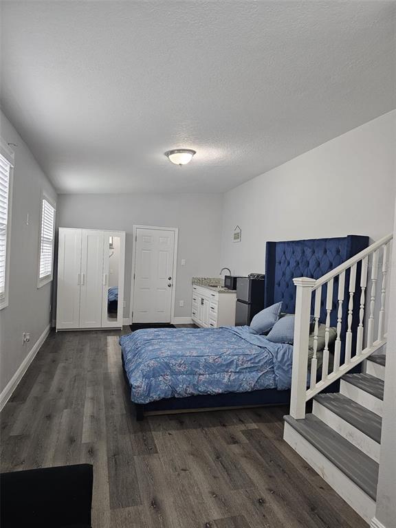A bedroom with a blue tufted headboard, a white wardrobe, and a kitchenette area — 6928 SALINAS DRIVE, ORLANDO, FL