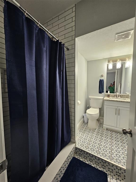 A bathroom features a navy shower curtain, white subway tile, and patterned floor tiles — 6928 SALINAS DRIVE, ORLANDO, FL