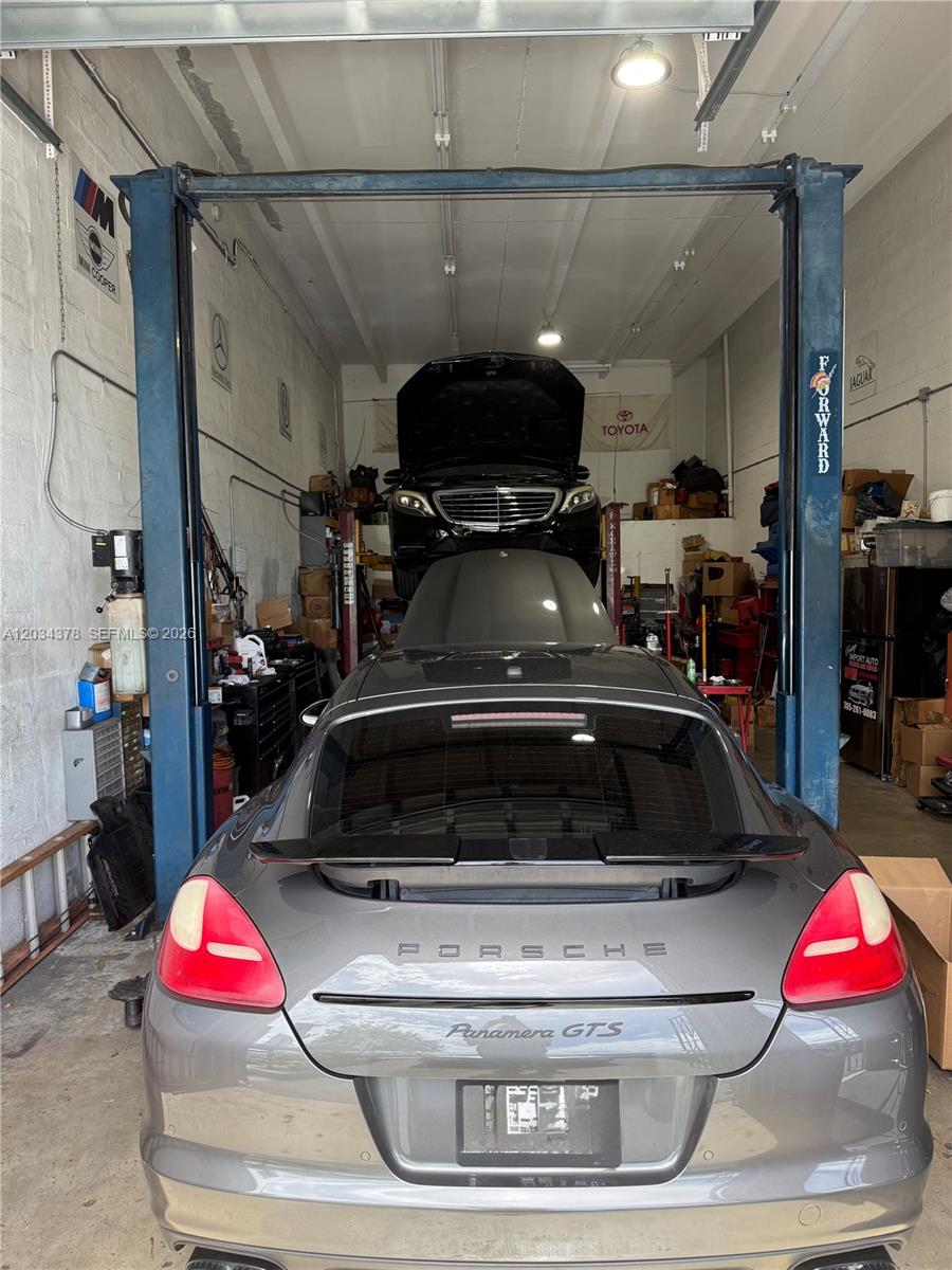 A vehicle repair shop features a gray Porsche Panamera GTS parked under a lifted Mercedes-Benz — 7013 SW 46 ST, Miami FL 33155, MIAMI, FL