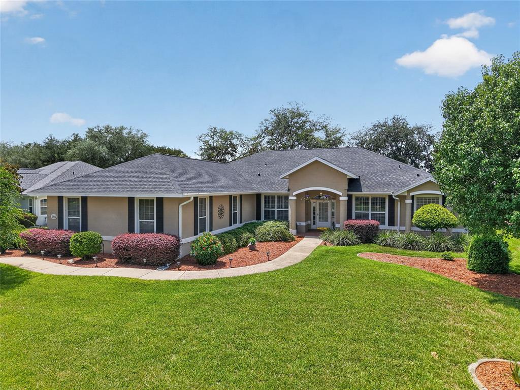 A single-story house with a tan stucco exterior, dark shutters, and a gray shingled roof — 349 LAKE DRIVE, OCALA, FL