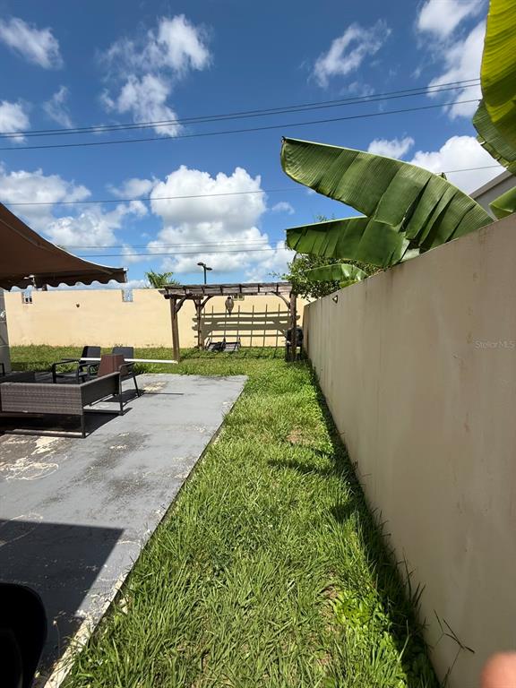 A backyard features a concrete patio, a wooden pergola, and a tall perimeter wall — Aurora 120 VEGA SERENA, VEGA BAJA, PR