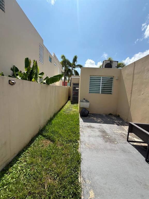 A narrow backyard features a patch of grass, a concrete patio, and a small building — Aurora 120 VEGA SERENA, VEGA BAJA, PR