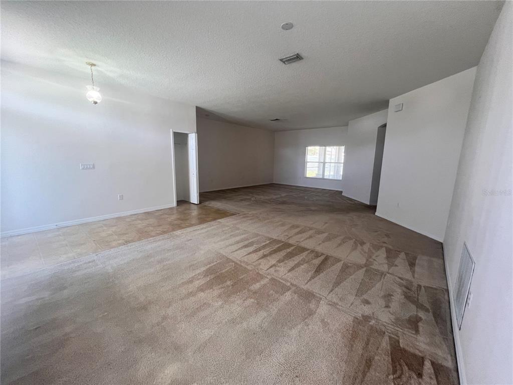 An open-concept living area features beige carpeting, tile flooring, and a small closet — 41 LOUISIANA DRIVE, PALM COAST, FL