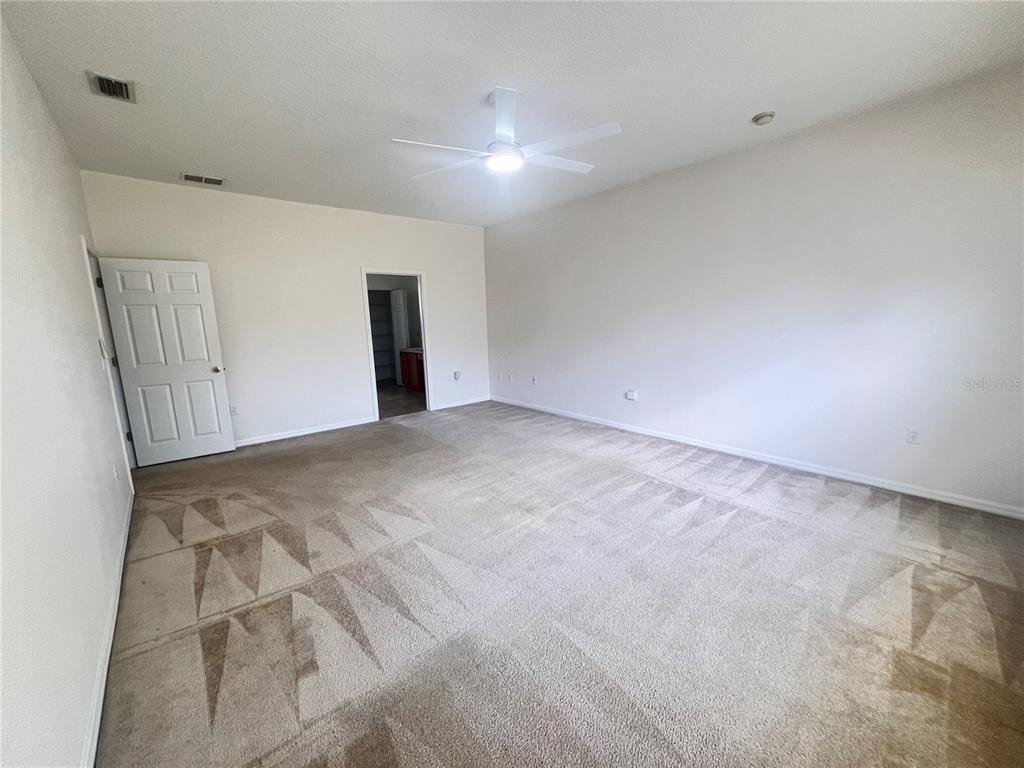 A spacious, carpeted bedroom features a ceiling fan, white walls, and two doorways — 41 LOUISIANA DRIVE, PALM COAST, FL