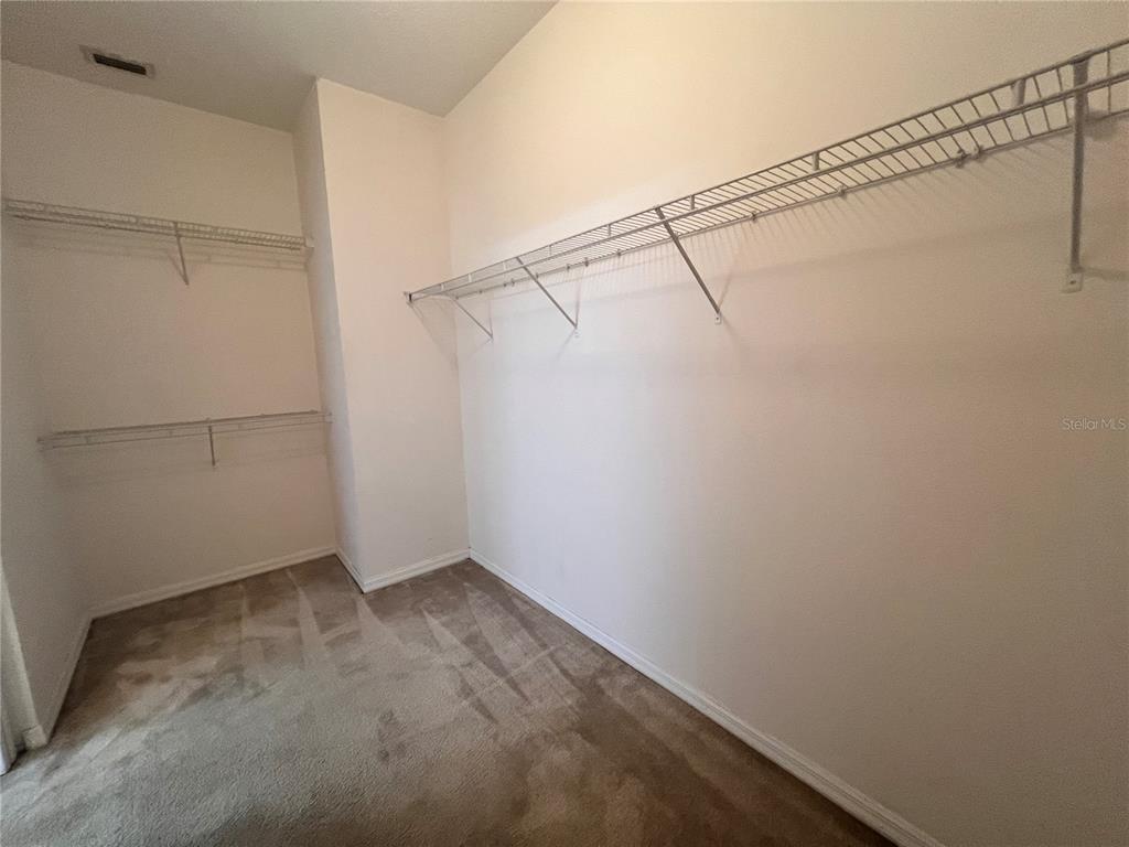 A walk-in closet features beige carpeting, white walls, and wire shelving units — 41 LOUISIANA DRIVE, PALM COAST, FL