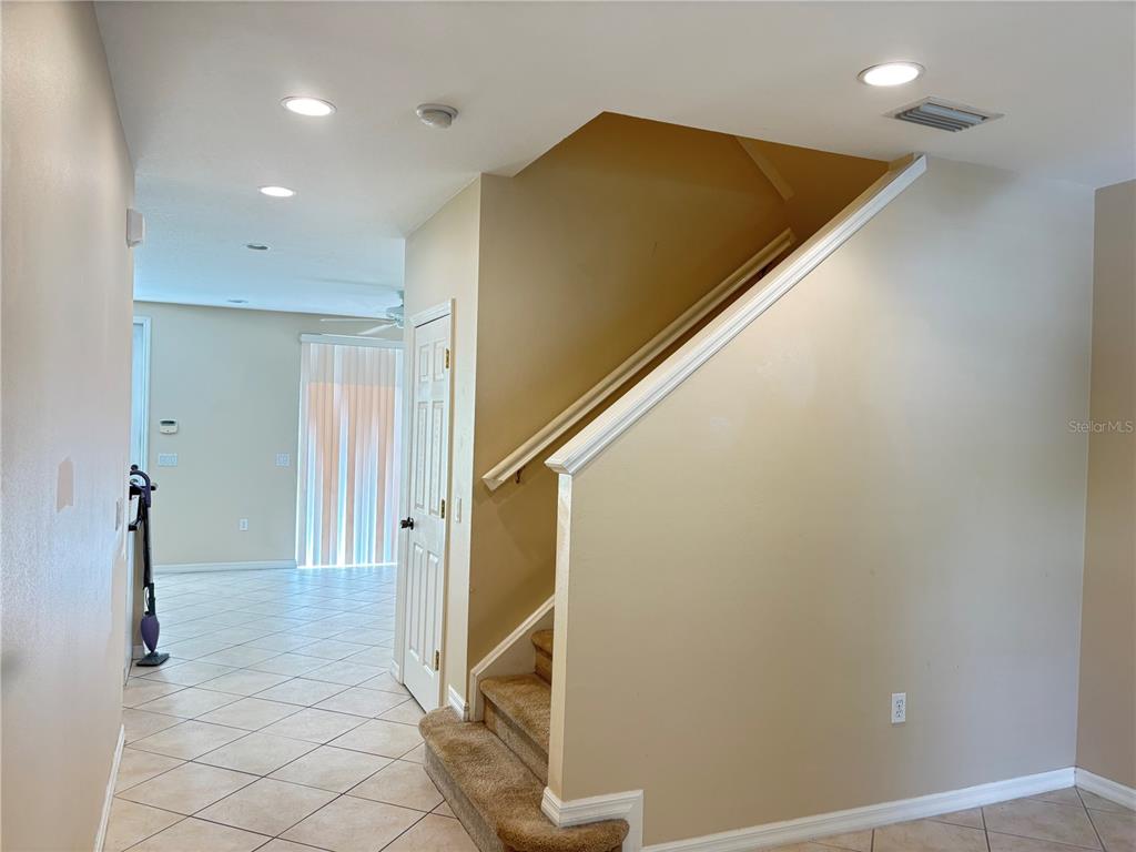 A carpeted staircase with a white railing sits next to a tiled living area — 5641 WHITEHEAD STREET, BRADENTON, FL