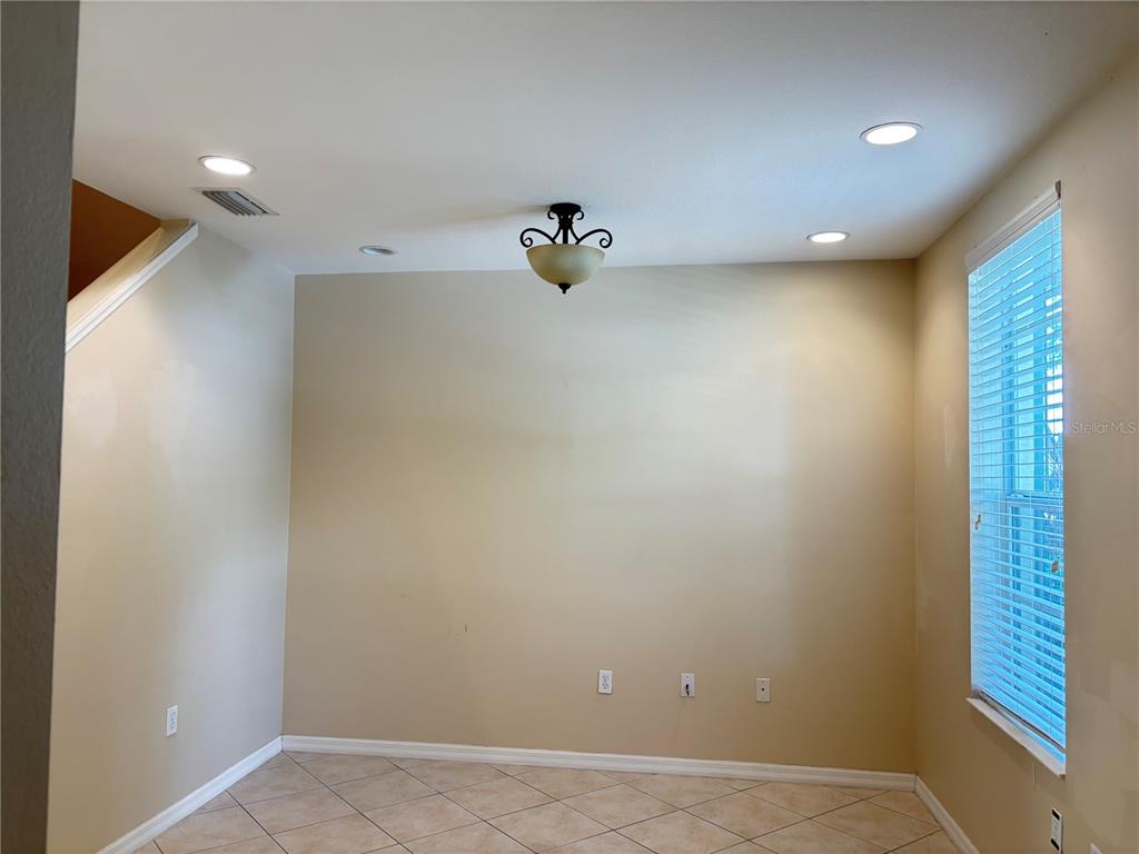 A dining area features beige walls, tile flooring, a central light fixture, and a window — 5641 WHITEHEAD STREET, BRADENTON, FL