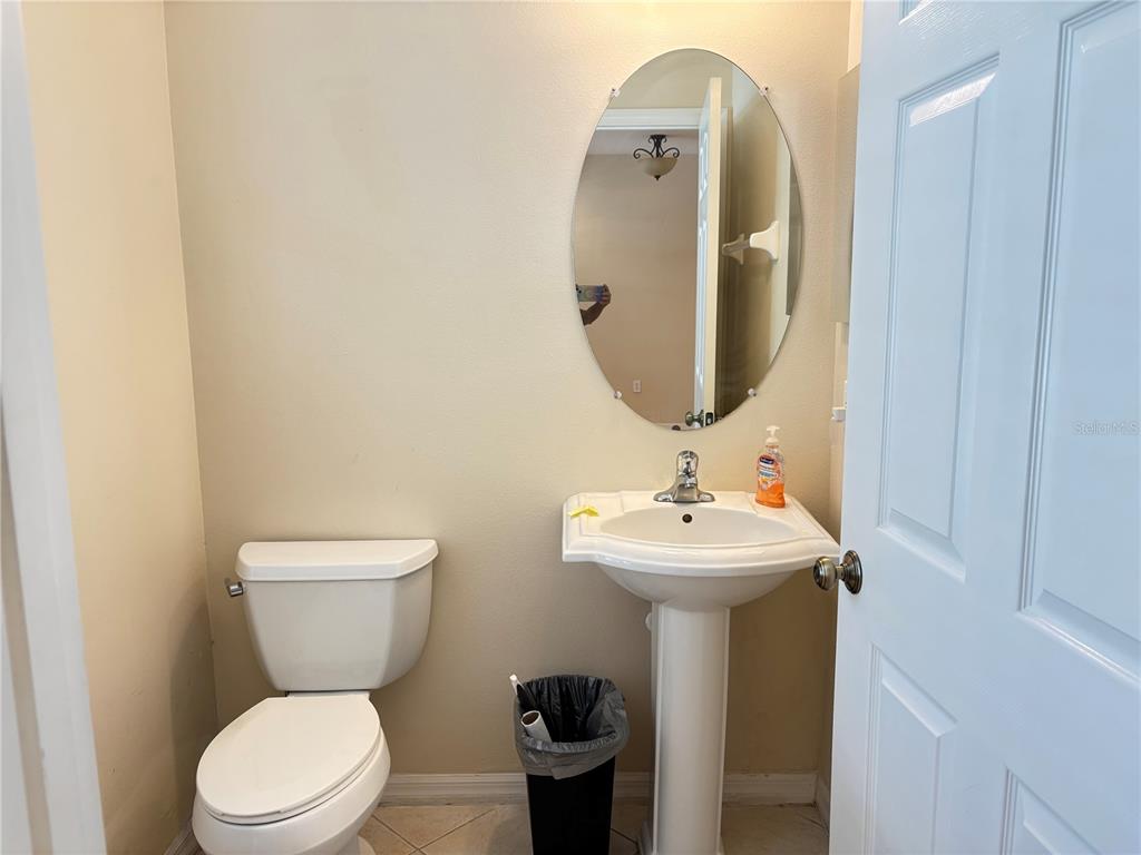 A small bathroom features a pedestal sink, an oval mirror, and a white toilet — 5641 WHITEHEAD STREET, BRADENTON, FL