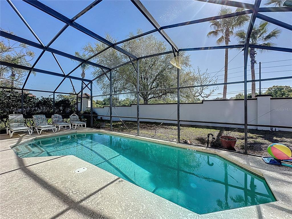 A swimming pool sits inside a screened-in lanai with lounge chairs on the concrete deck — 110 RUBINO DRIVE, DAVENPORT, FL