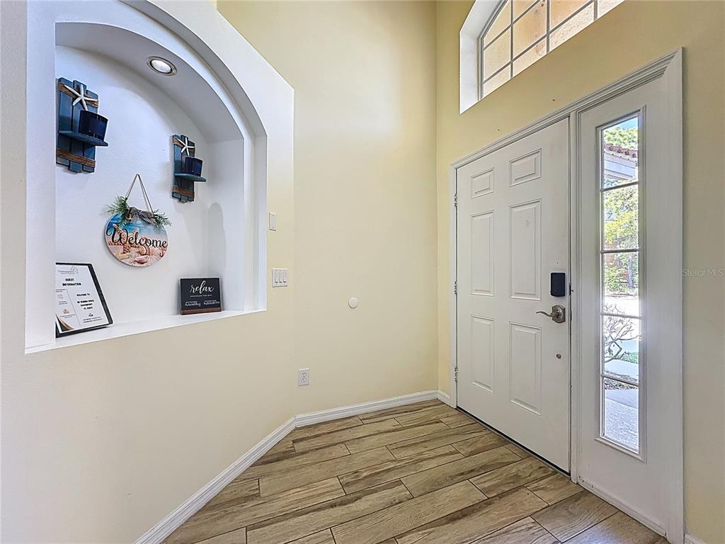 An entryway features wood-look tile flooring, a white front door, and a recessed wall niche — 110 RUBINO DRIVE, DAVENPORT, FL