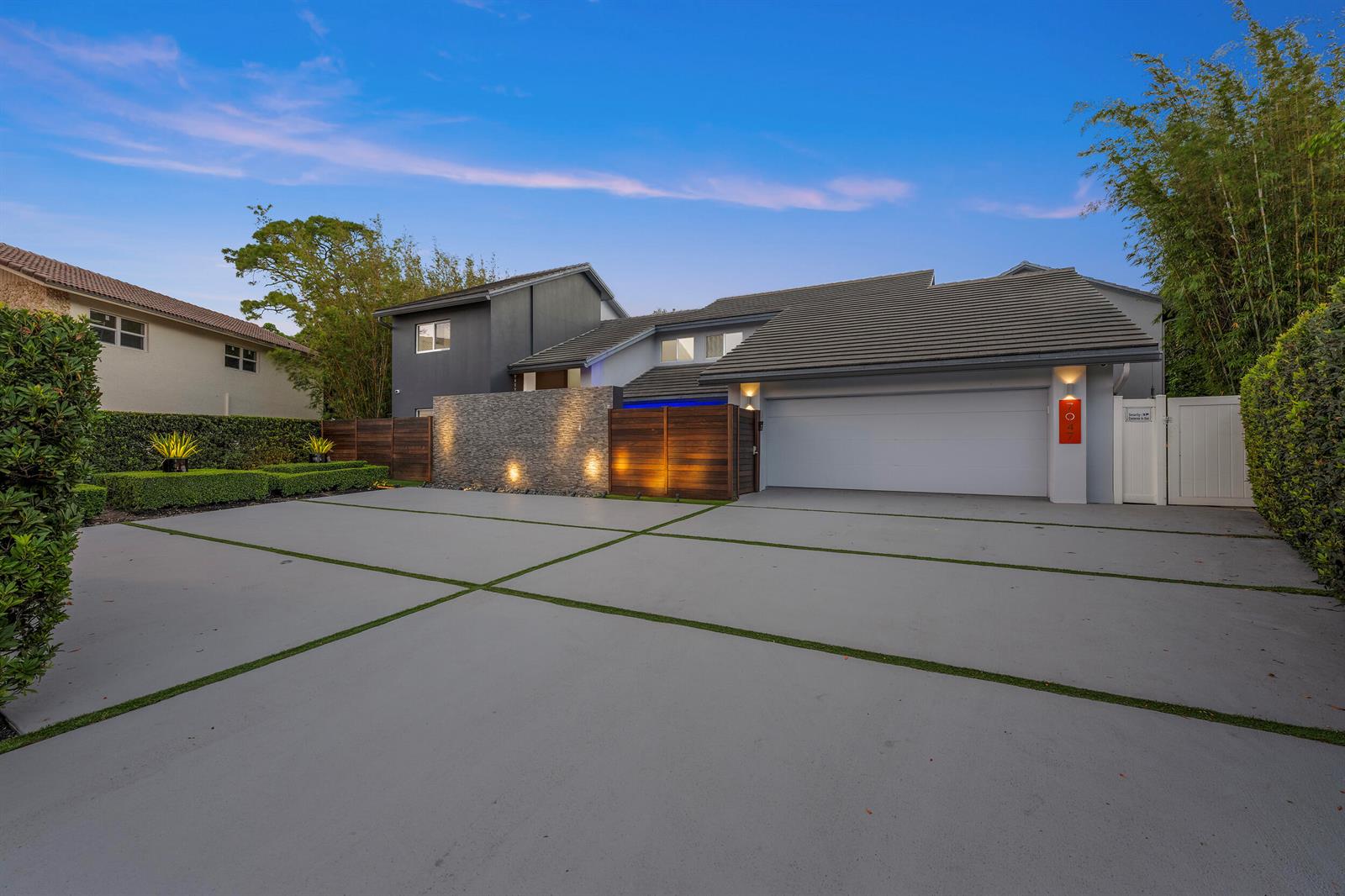 A modern house exterior with a large concrete driveway, stone accent wall, and garage door — 7047 San Sebastian Circle, Boca Raton FL 33433, BOCA RATON, FL