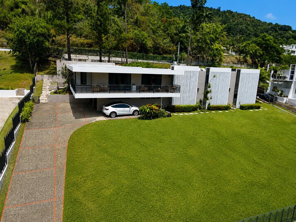 An aerial view shows a modern white house with a balcony, carport, and large lawn — B7 CALLE INDUSTRIA, CAGUAS, PR