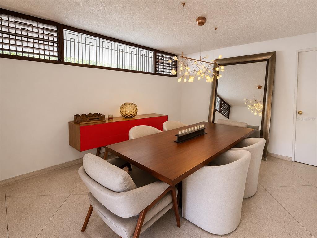 A dining room features a wooden table, upholstered chairs, a red sideboard, and a large mirror — B7 CALLE INDUSTRIA, CAGUAS, PR