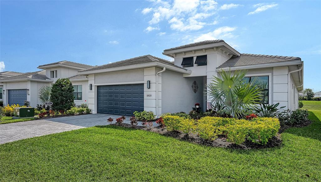 A modern single-story house with a gray garage, tile roof, and landscaped front yard — 18020 CRESSWIND TERRACE, BRADENTON, FL