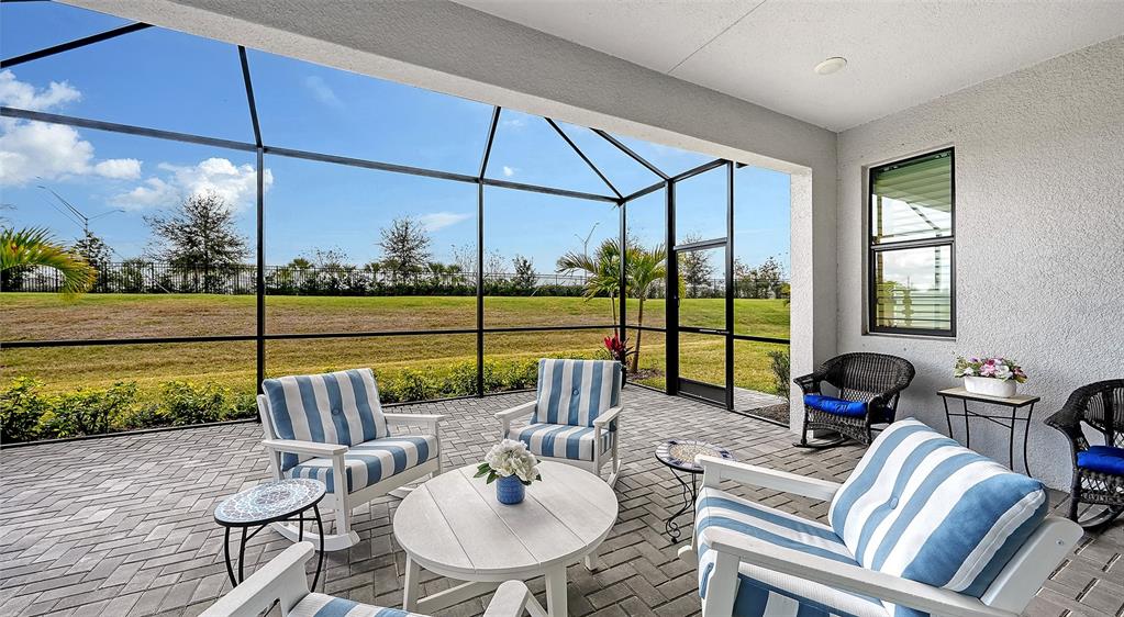 A screened-in patio features a paver floor, outdoor furniture, and a view of a grassy yard — 18020 CRESSWIND TERRACE, BRADENTON, FL