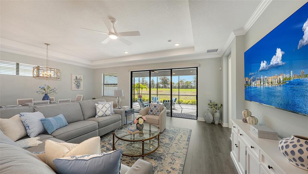 A living room with a gray sectional, glass coffee table, and large sliding doors to a patio — 18020 CRESSWIND TERRACE, BRADENTON, FL