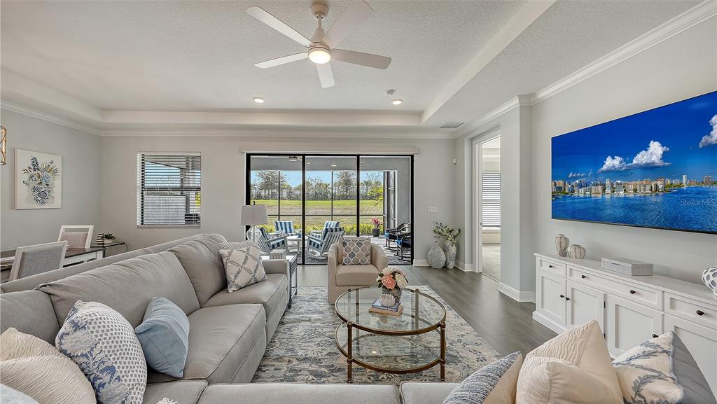 A living room features a grey sectional sofa, a glass coffee table, and a large television — 18020 CRESSWIND TERRACE, BRADENTON, FL