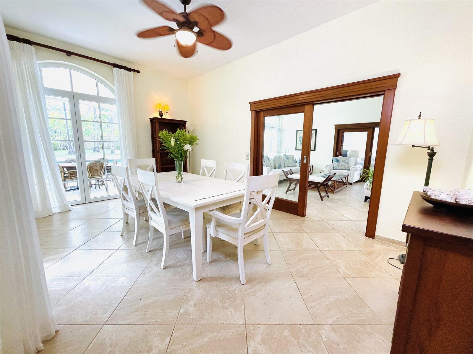 A dining room with a white table, chairs, tile floors, and a view of a patio — 123 Sea Horse Ranch, FL