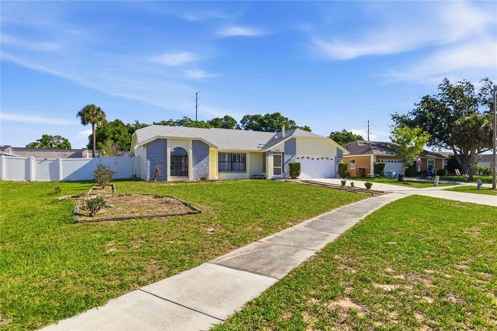 A single-story house with a light-colored exterior, a two-car garage, and a front lawn — 7771 INDIAN RIDGE TRAIL N, KISSIMMEE, FL